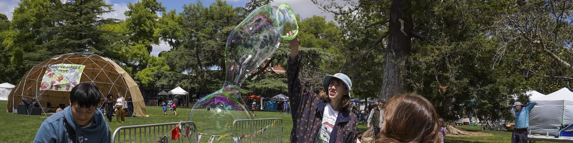 Person plays with a large bubble wand at Whole Earth Festival