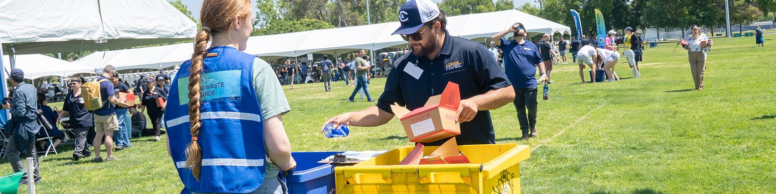 UC Davis Zero Waste Guide helping a staff member sort their waste at an outdoor event.