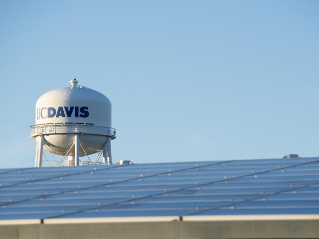 On-site solar panels shade parking spaces at Visitor Parking Lot 1 near the Mondavi Center, with the UC Davis Water Tower behind; January 2020. 