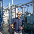 Man stands among pipes, tanks and other equipment