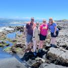 Eric O'Brien posing with family at a rocky beach shore.