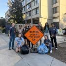 Students pose with trash bags and a sign that reads "Warning Entering Zero Waste Zone"